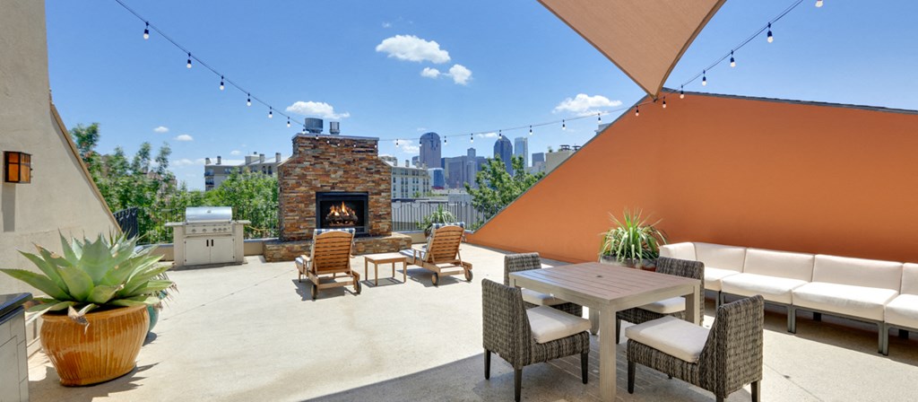 a rooftop patio with a table and chairs and a fireplace