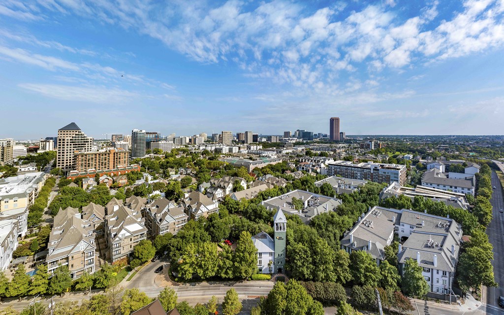 A cityscape with a mix of residential and commercial buildings under a clear sky.