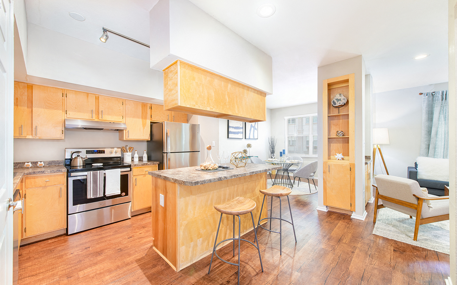 a kitchen with wooden cabinets and a bar with three stools