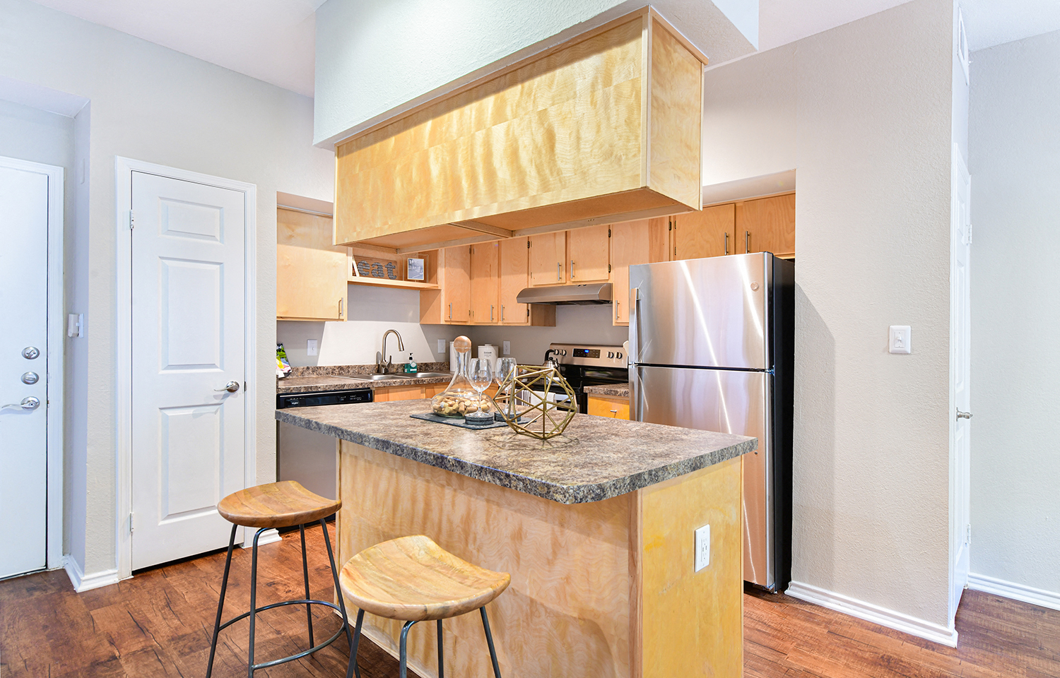 a kitchen with stainless steel appliances and a counter with two stools
