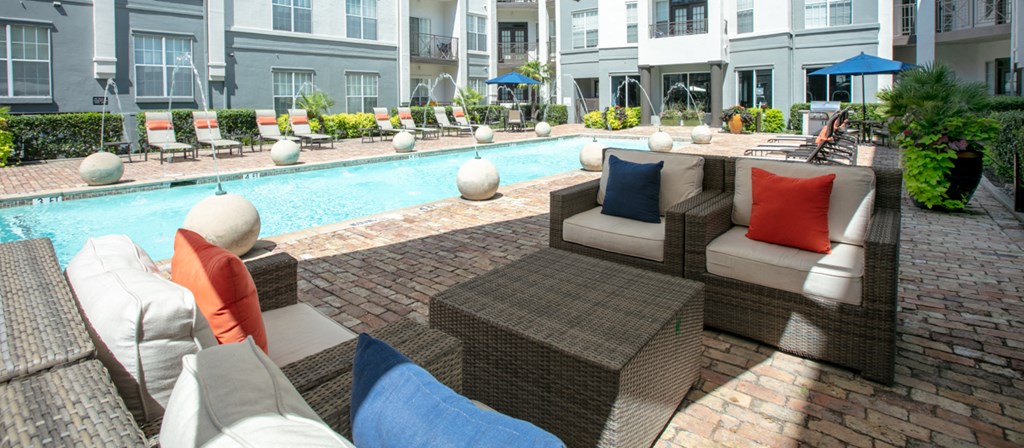 a swimming pool with lounge furniture in front of a building