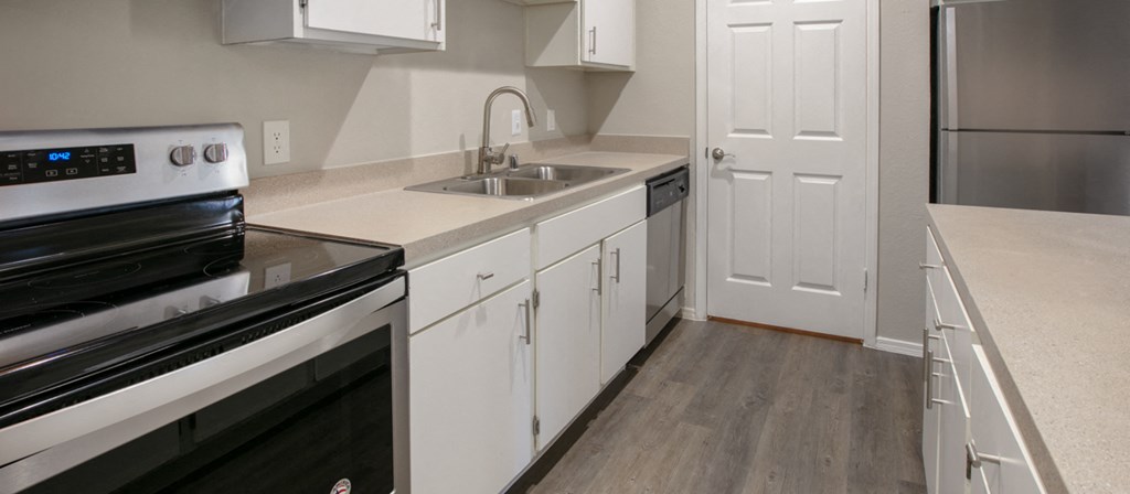 an empty kitchen with white cabinets and stainless steel appliances