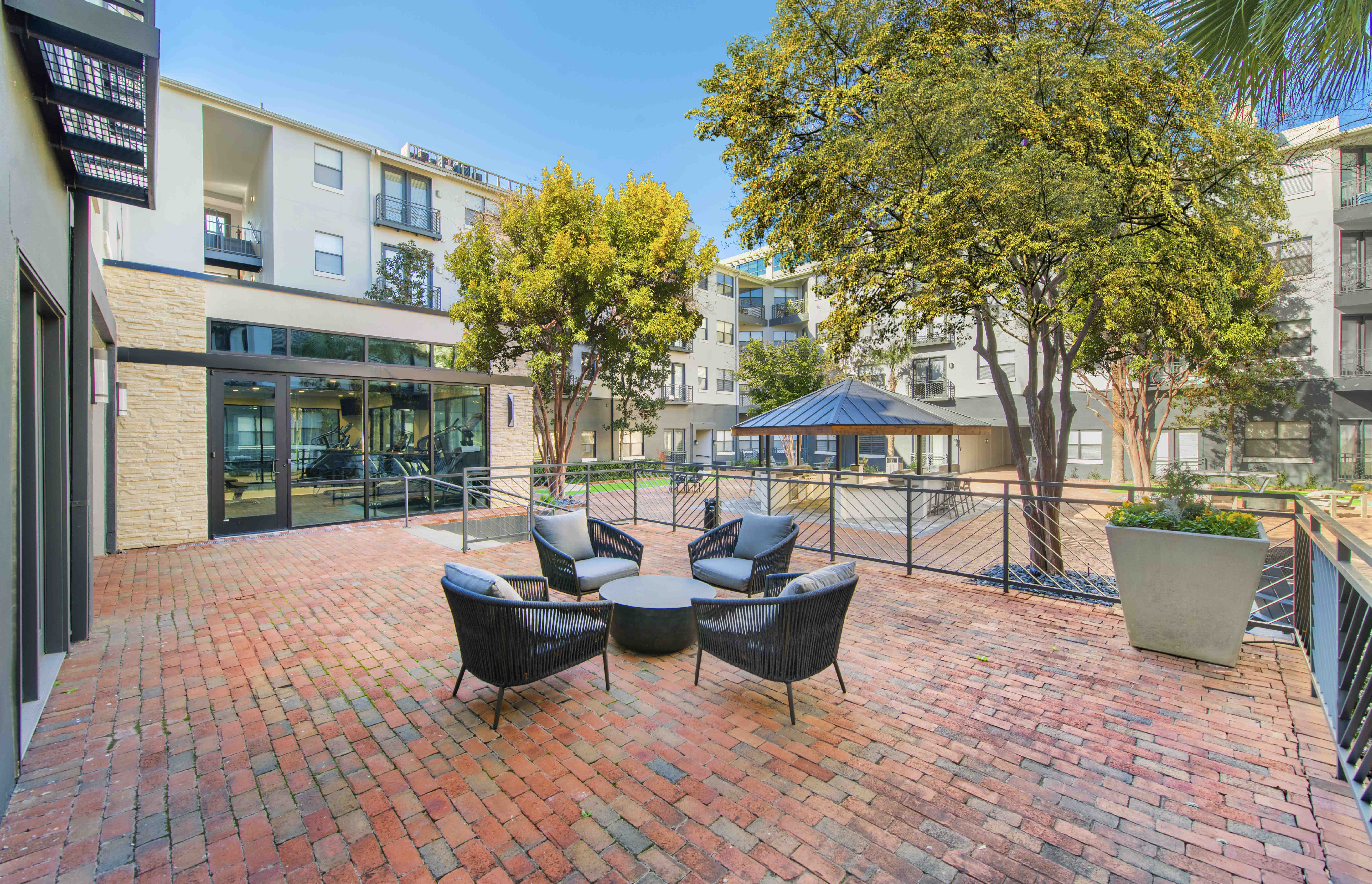 a patio with chairs and a table in front of an apartment building