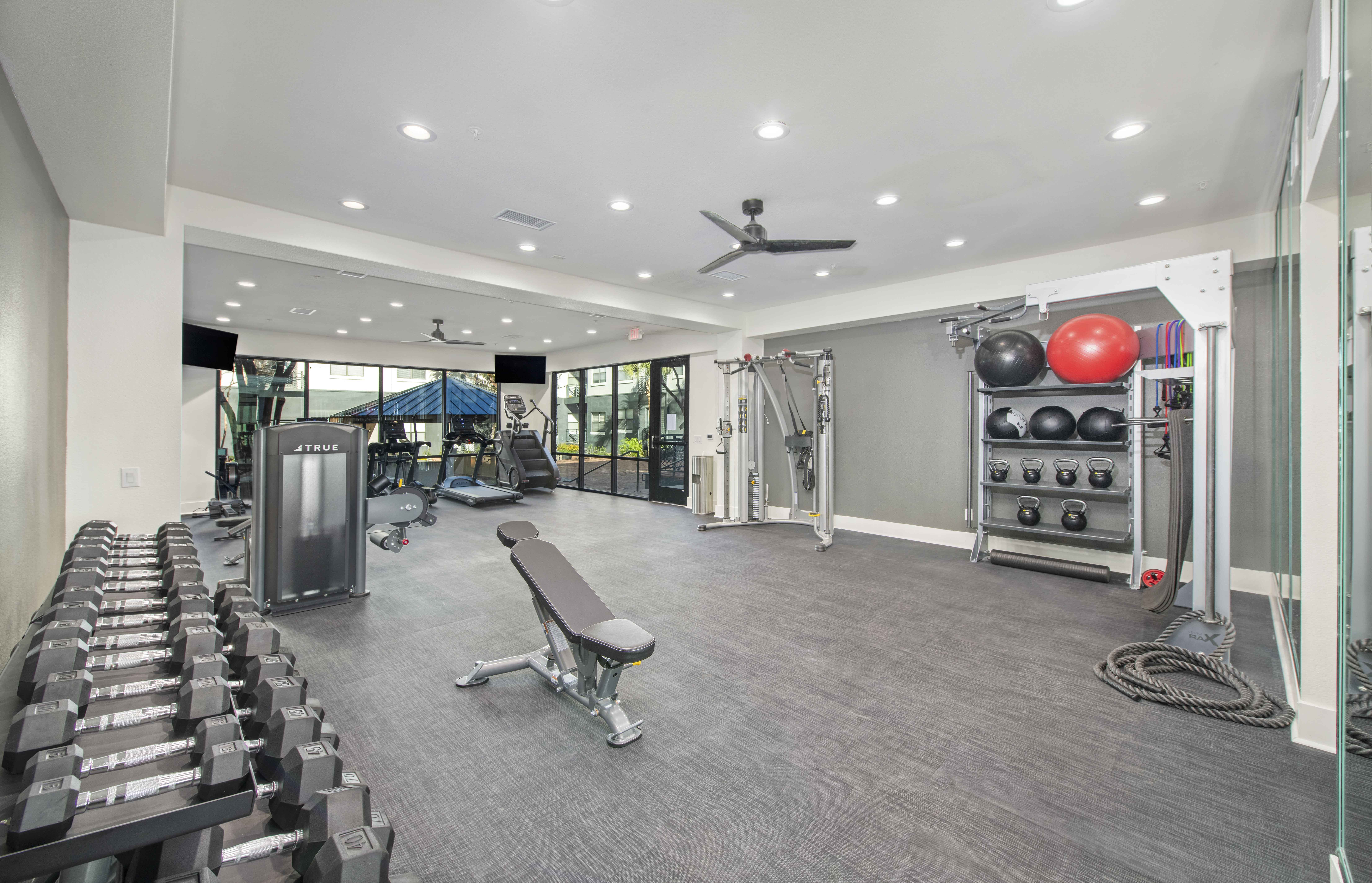 a gym with weights and cardio equipment in a building with glass doors