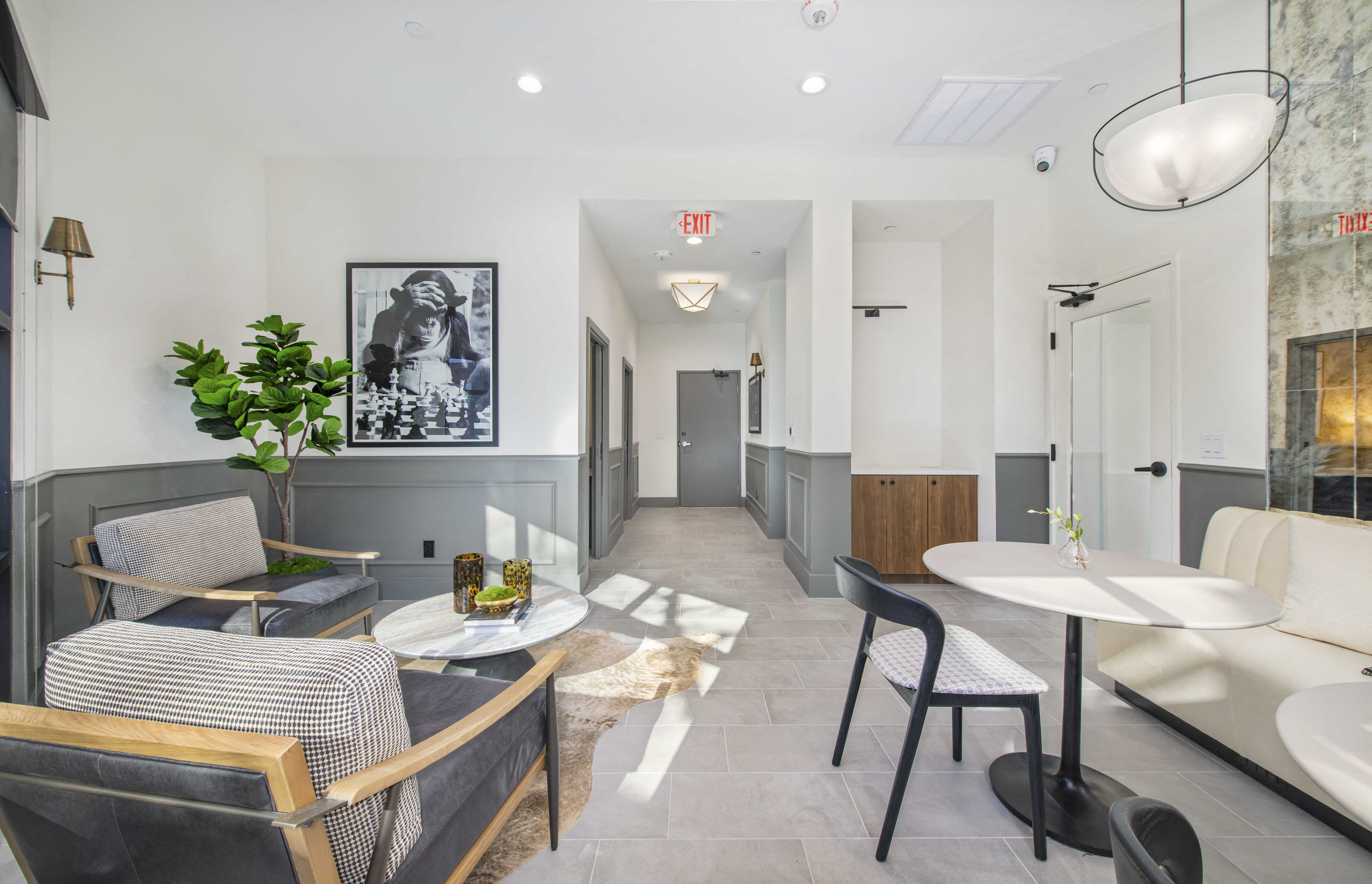 a living room with chairs and tables and a hallway with a door