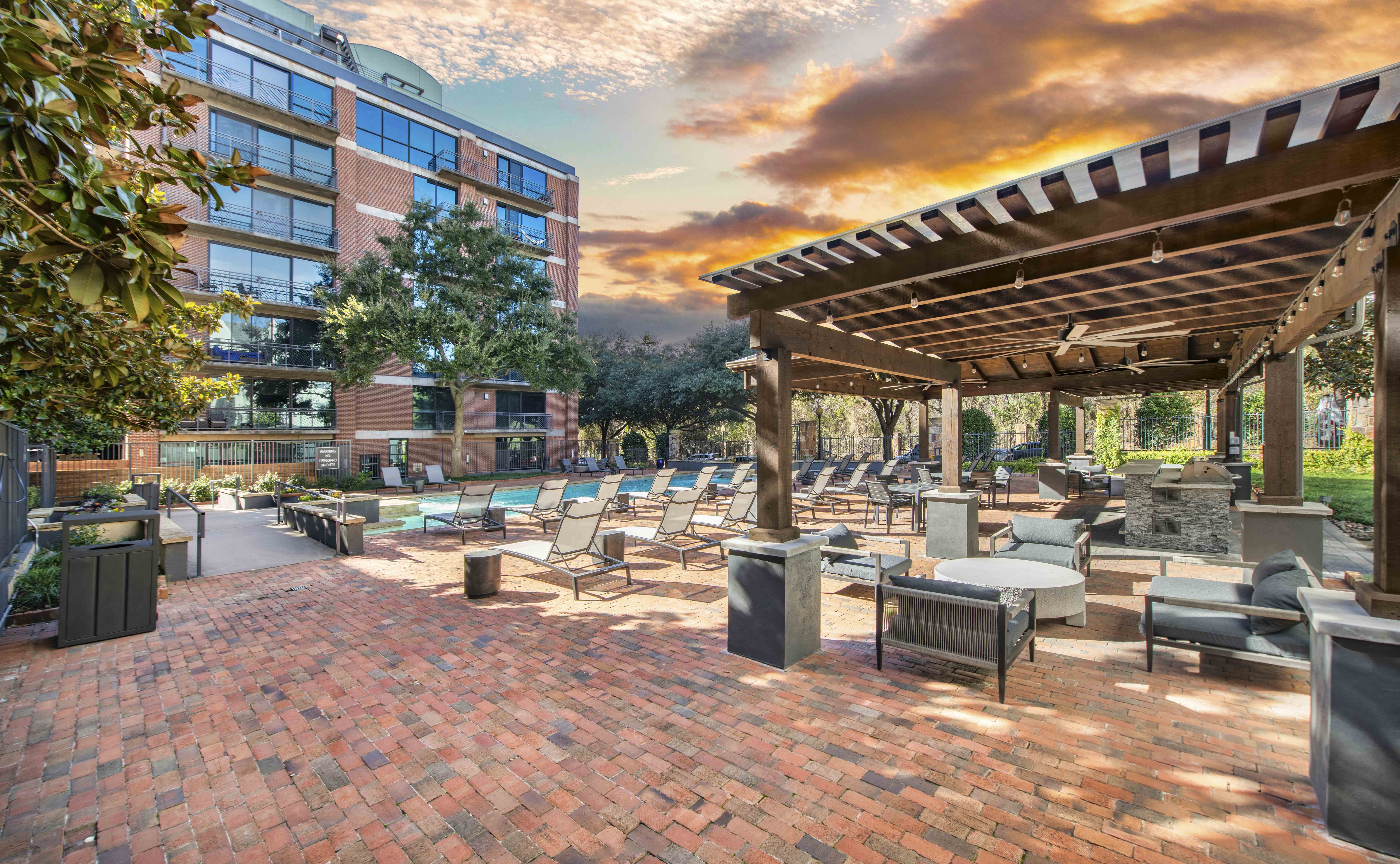 a patio with tables and chairs and a building with a sunset in the background