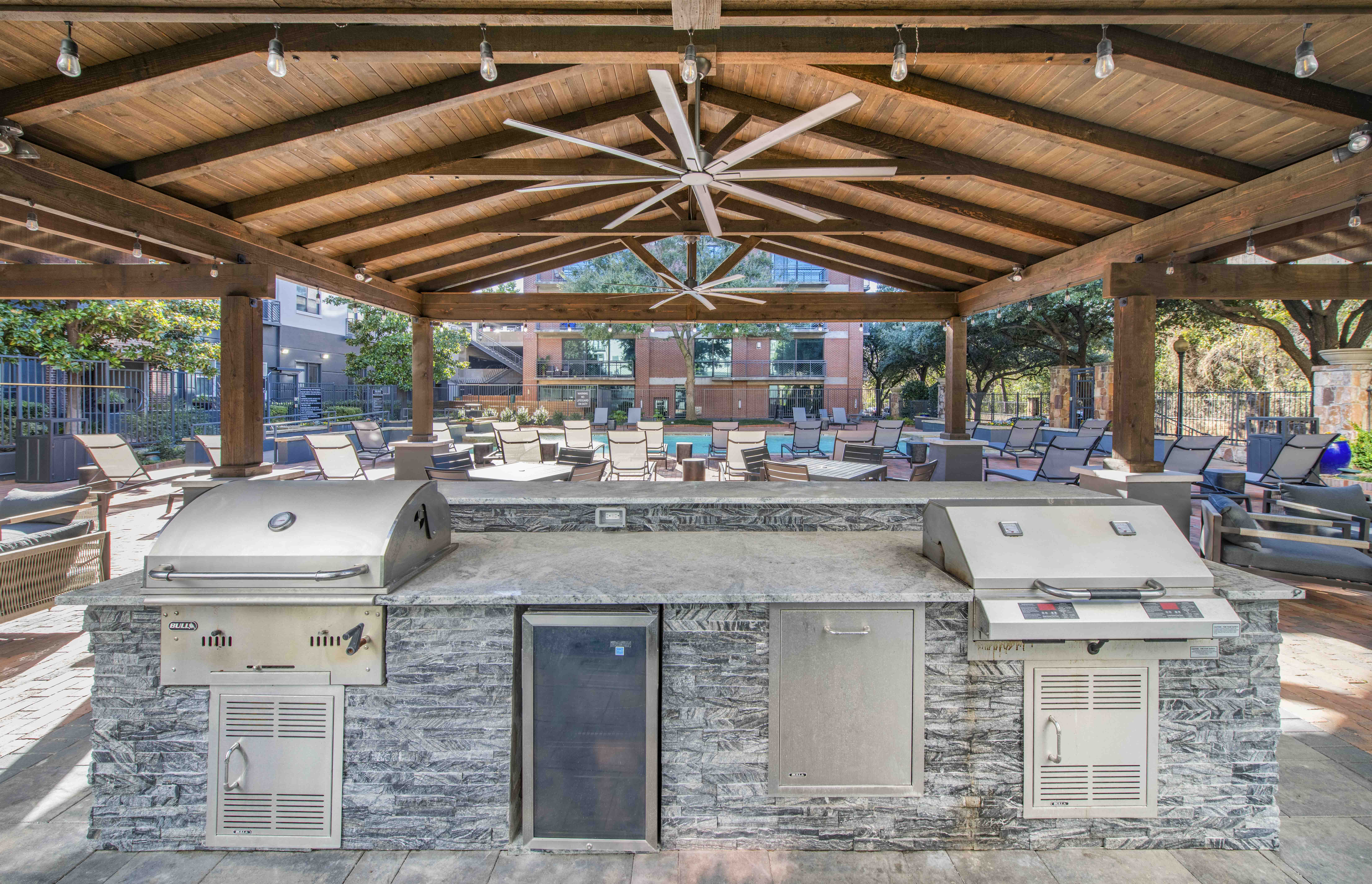 a patio with a grill and a counter with two refrigerators