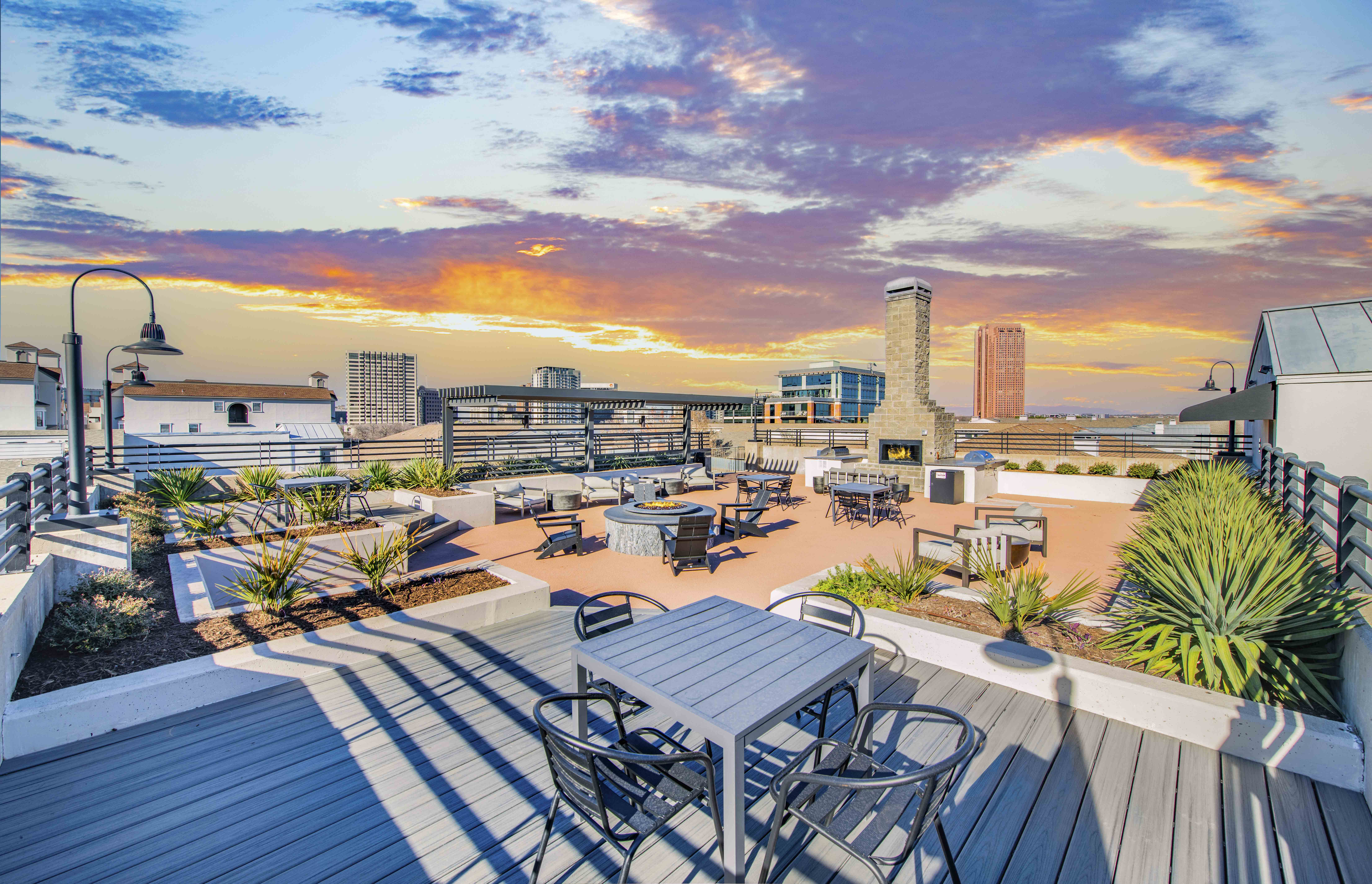 a rooftop patio with tables and chairs and a sunset in the background