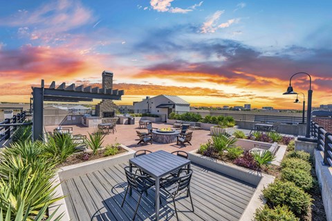 A patio with a table and chairs overlooks a sunset.