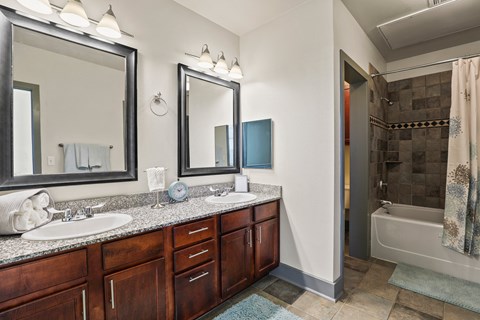 a bathroom with two sinks and a shower and two mirrors