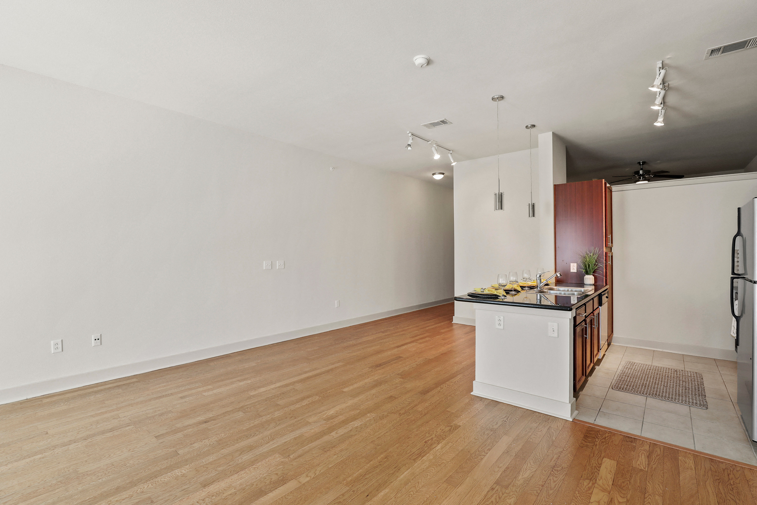 a living room and kitchen with a wood floor and white walls