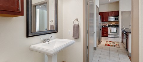 a bathroom with a sink and a mirror and a kitchen