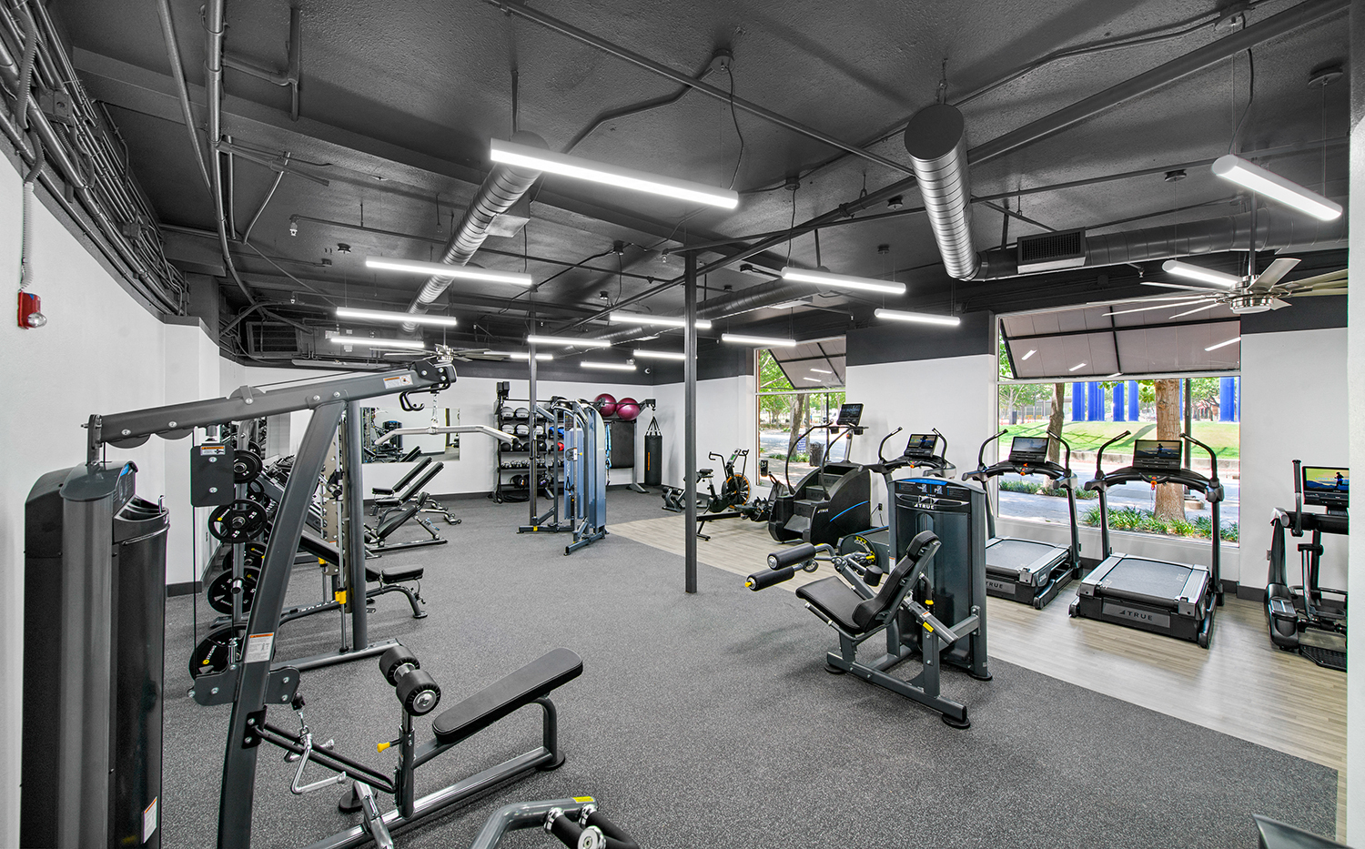 a gym with weights and other exercise equipment in a building with windows