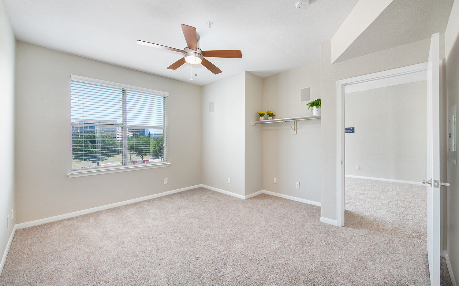 an empty living room with a ceiling fan and a window