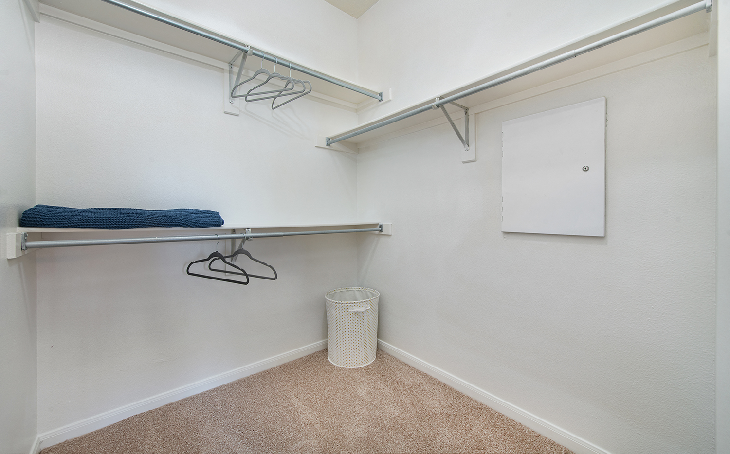 a spacious closet with shelves and a white wall and a trash can