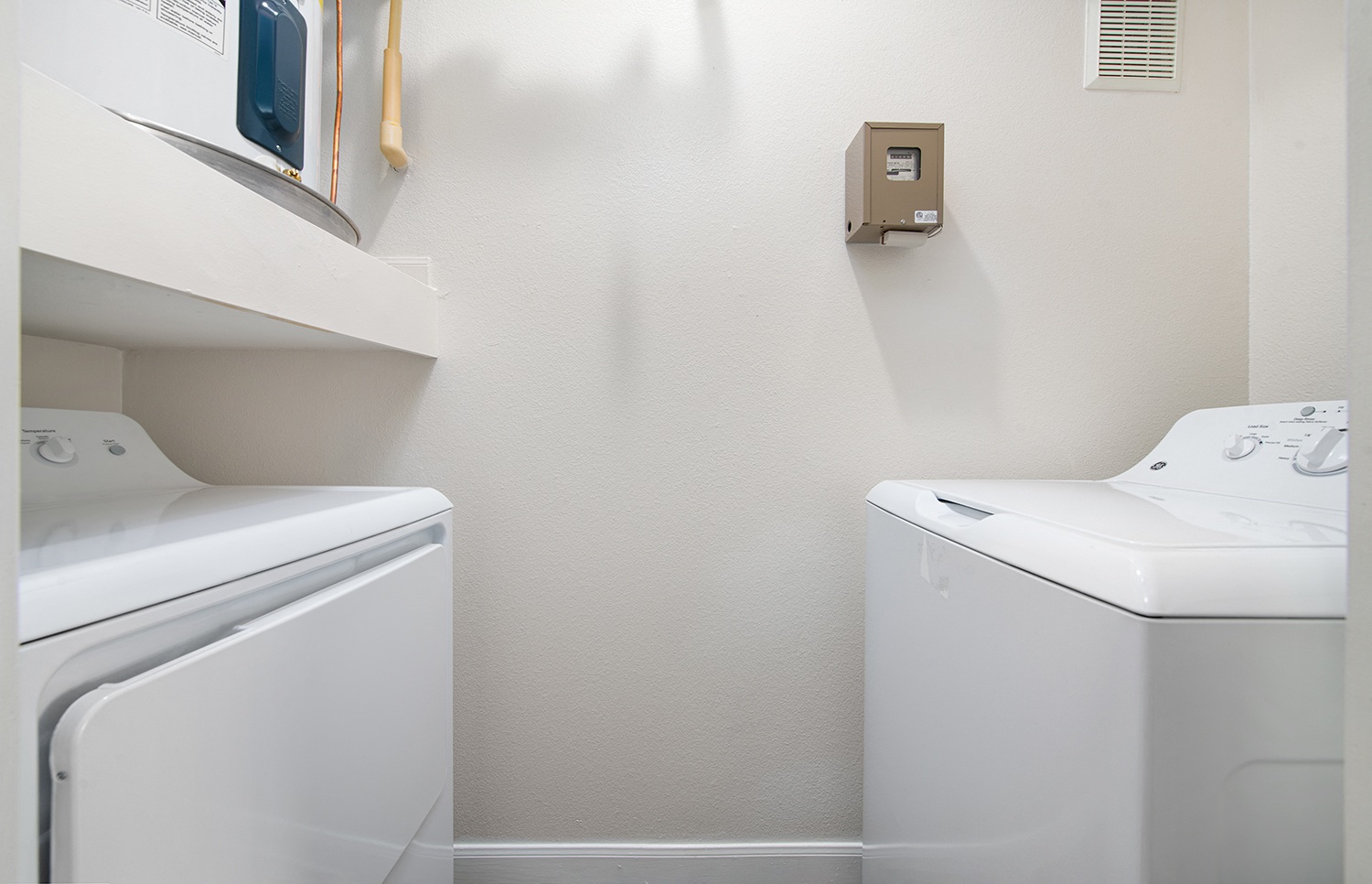 an empty laundry room with a washer and dryer and a white utility closet