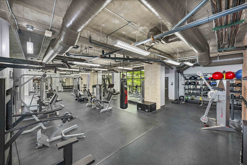 a gym with weights and cardio equipment in a building with cement floors