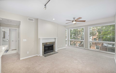 an empty living room with a fireplace and a ceiling fan