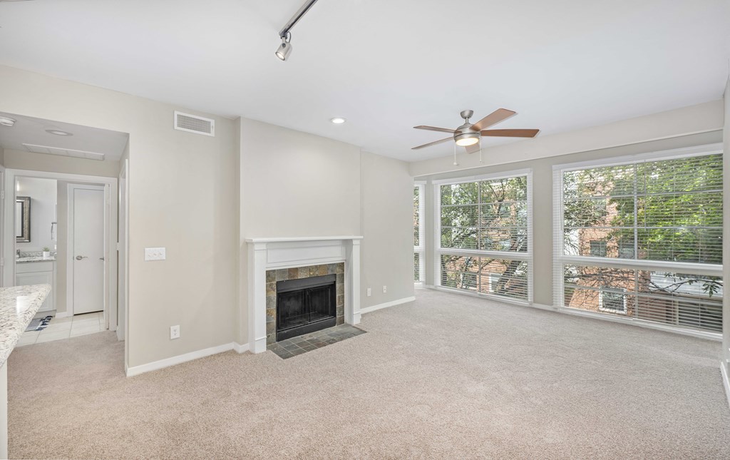 an empty living room with a fireplace and a ceiling fan