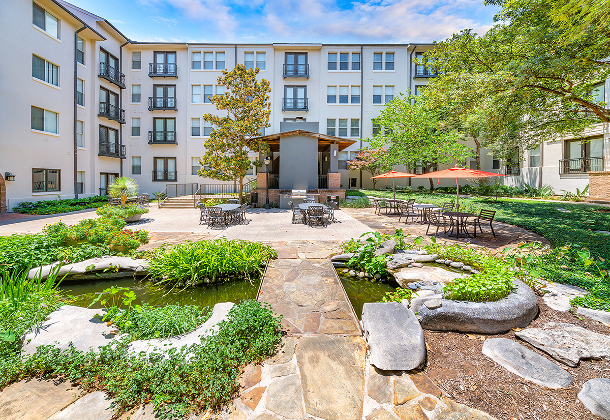 a courtyard with a fountain and tables and chairs in front of a building
