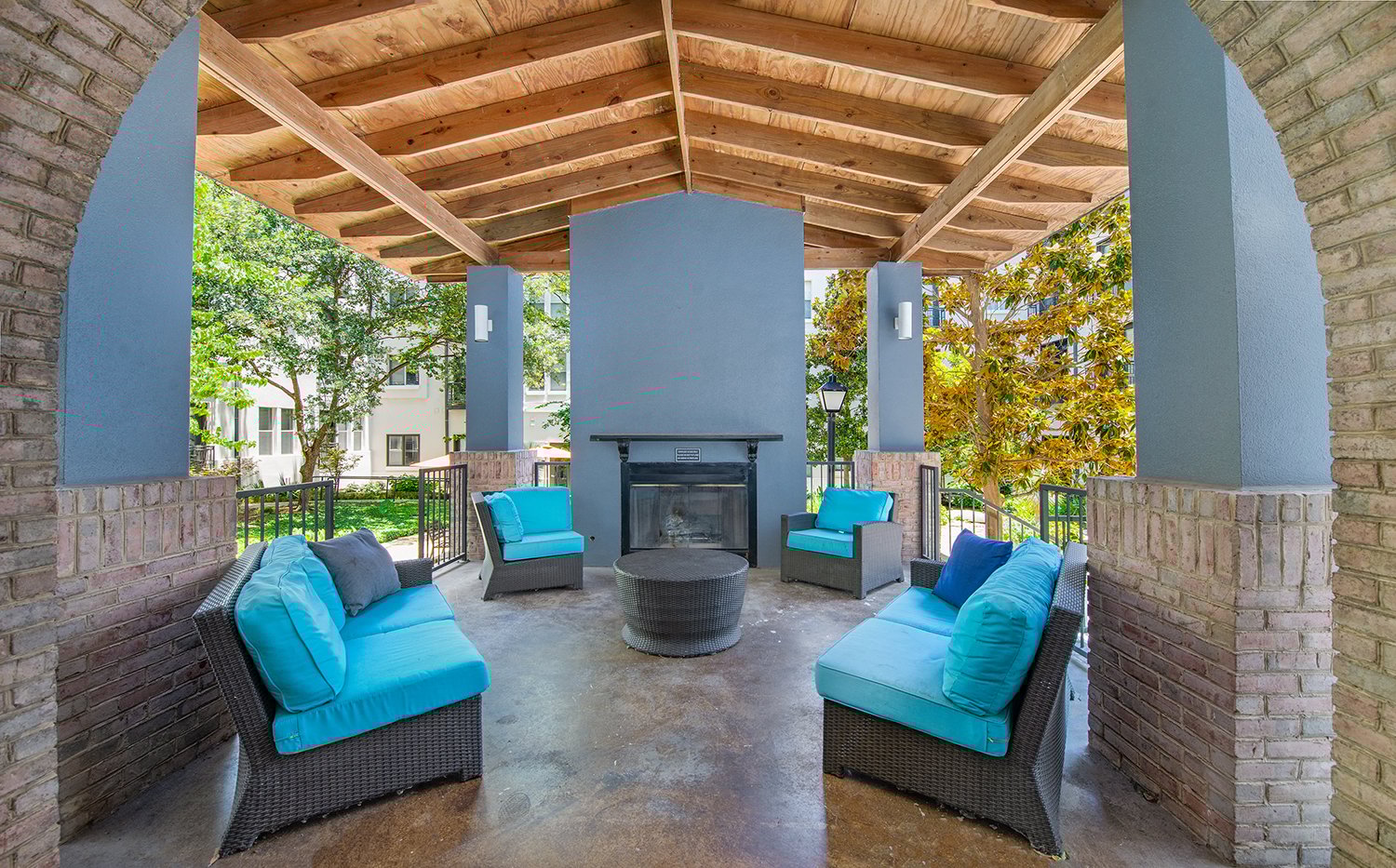 a patio with blue couches and chairs and a fireplace