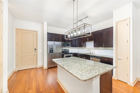 A kitchen with a granite counter top and stainless steel appliances.
