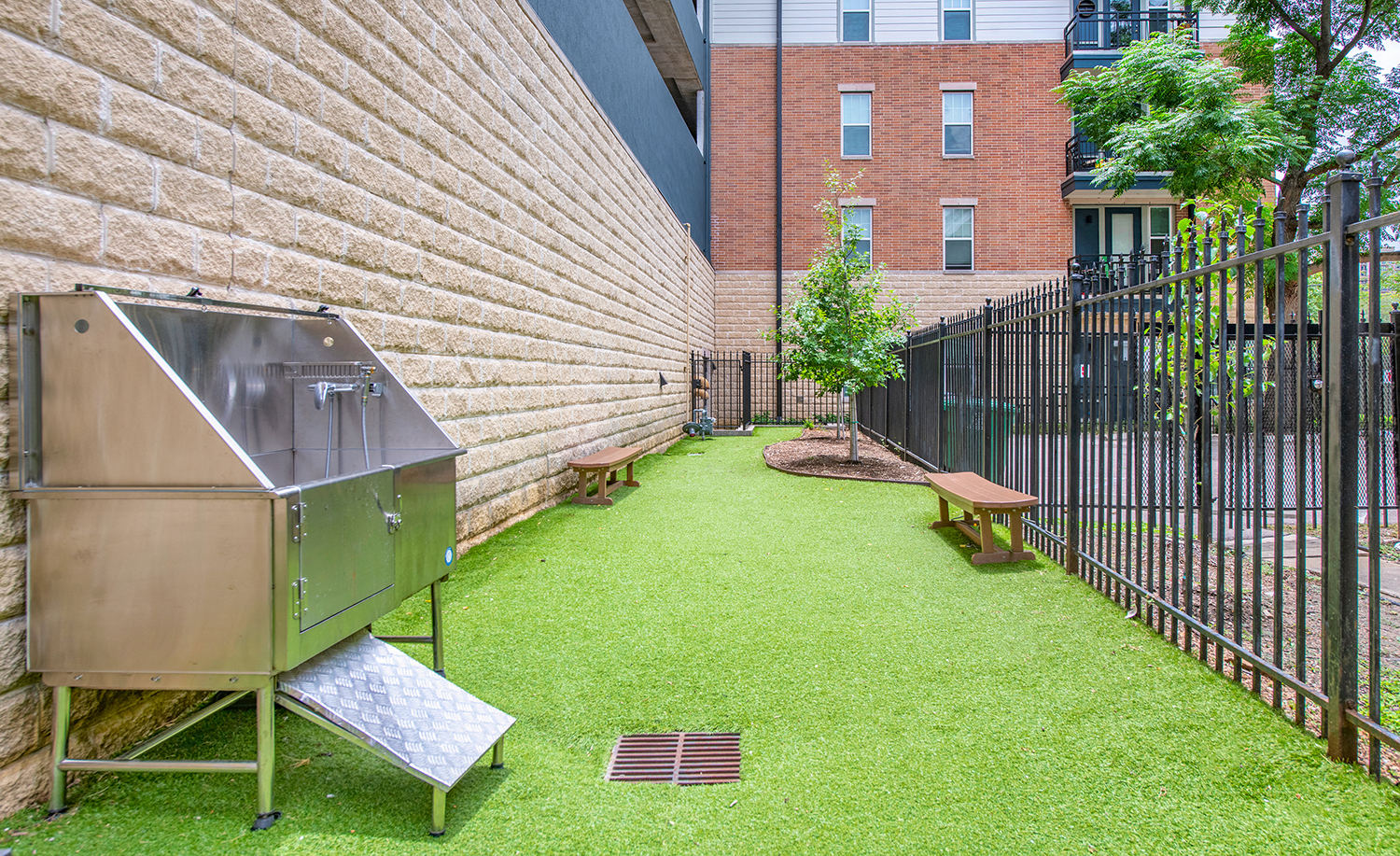 a yard with benches and a stainless steel barbecue grill