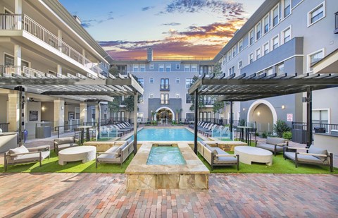 a courtyard with a pool and lounge chairs in front of a building