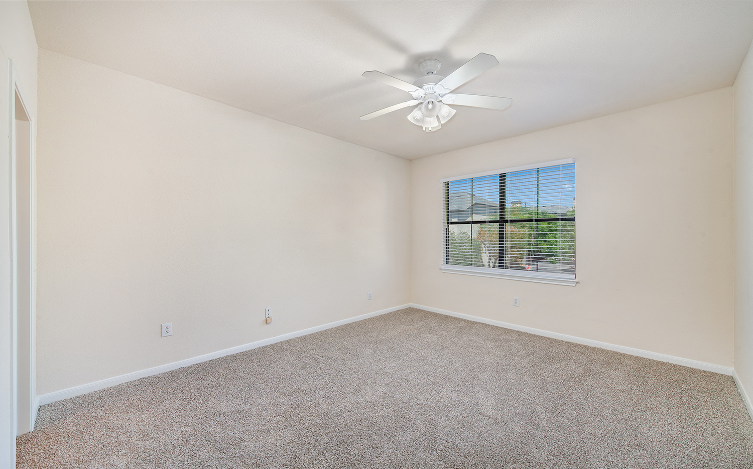 a spacious living room with carpet and a ceiling fan