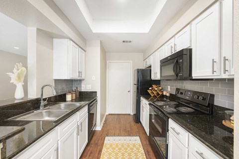 A kitchen with black countertops and white cabinets.