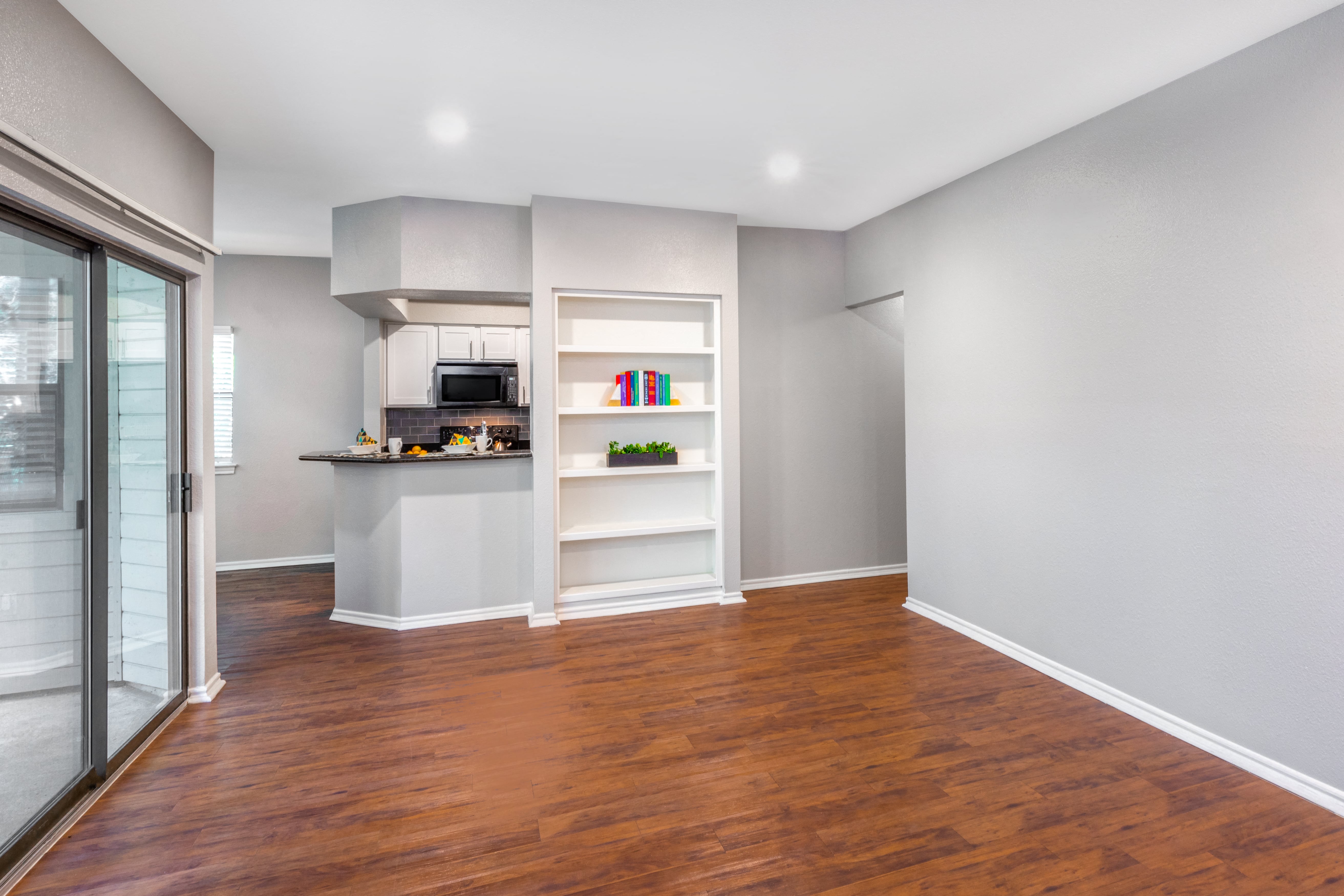 an empty room with a kitchen and a glass door