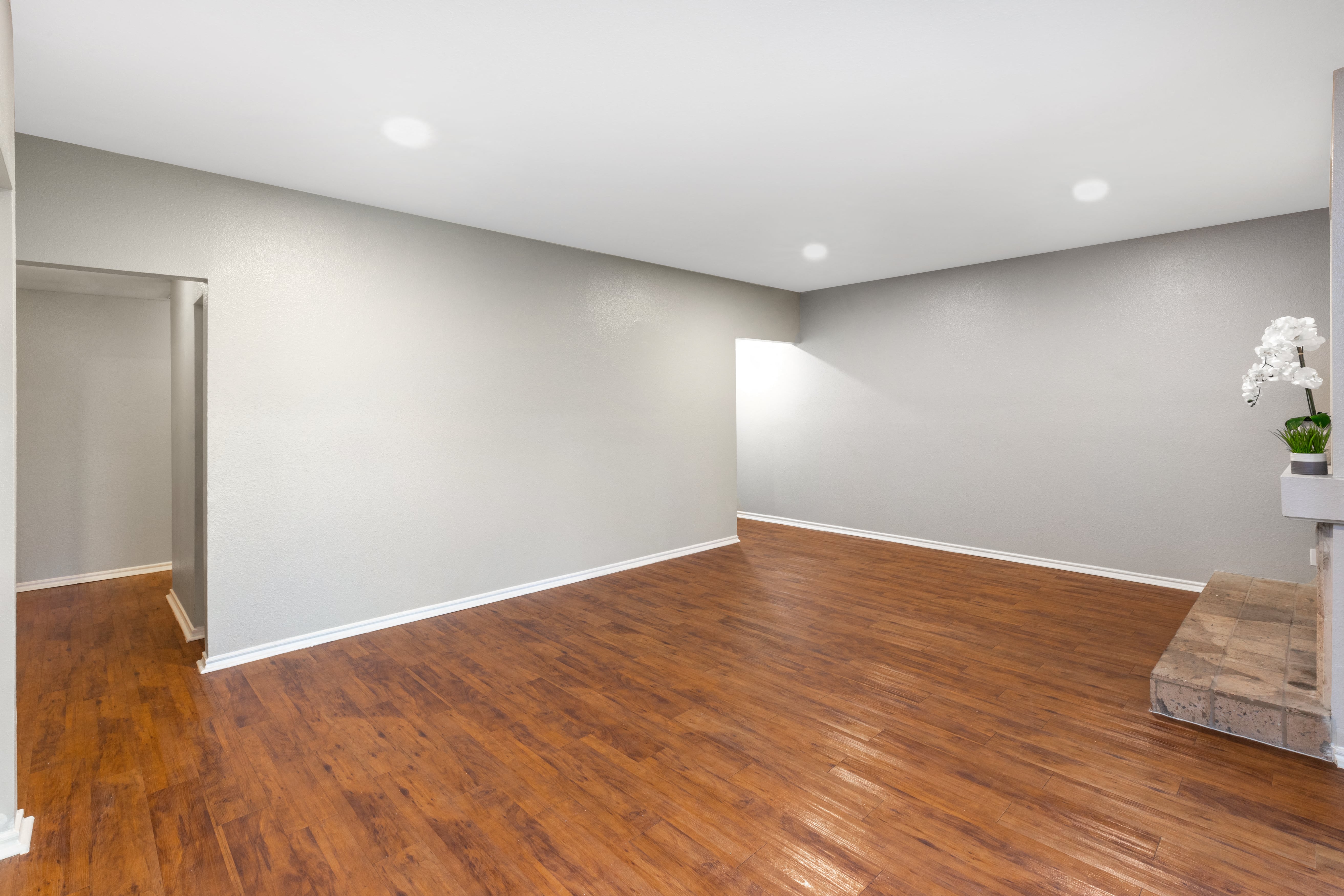 an empty living room with wood floors and white walls