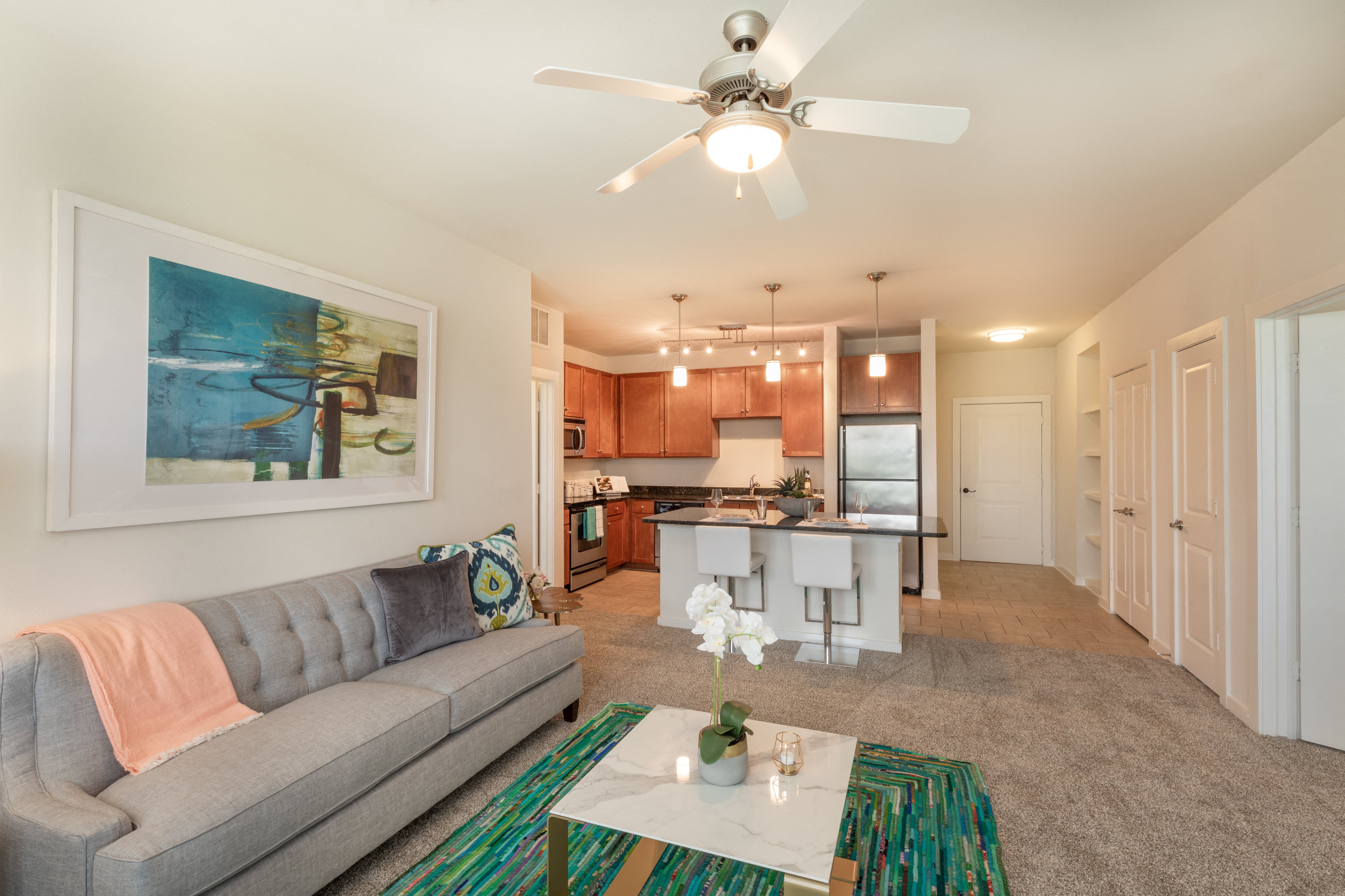 a living room and kitchen with a ceiling fan and a couch
