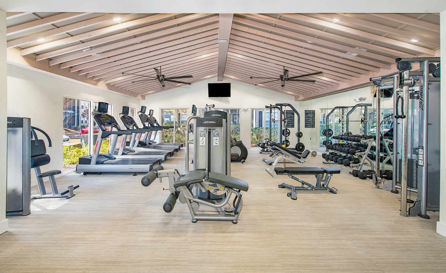 a gym with cardio equipment and weights on the floor