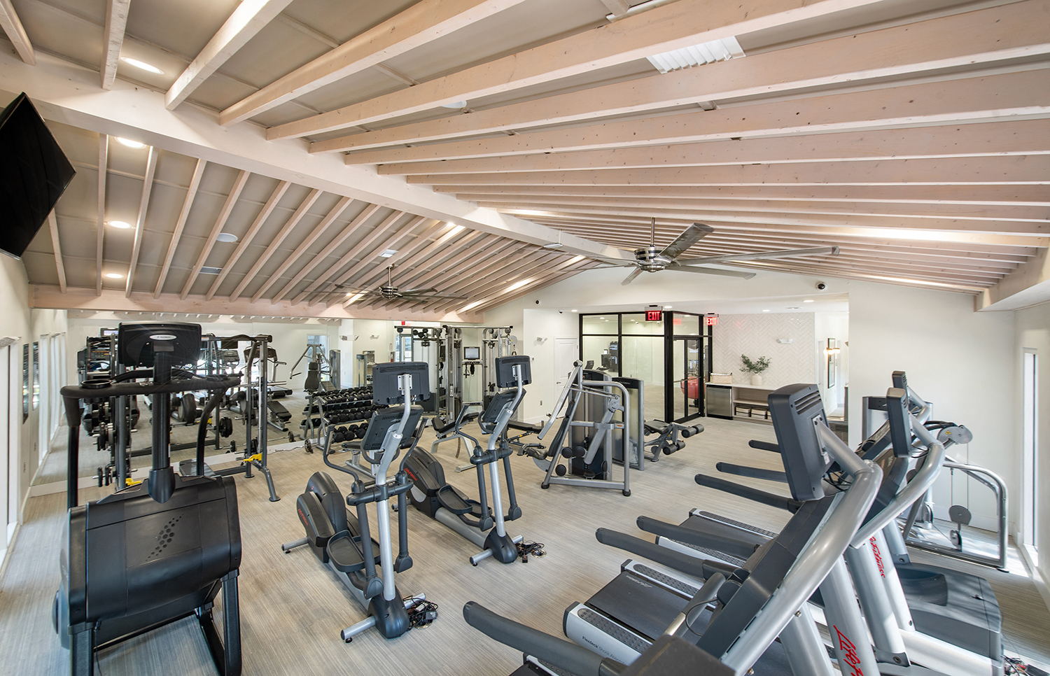 a gym with cardio equipment and weights on a wooden floor