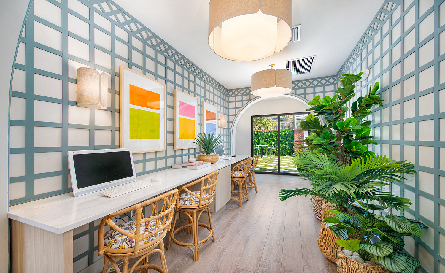 a room with a computer desk and chairs and a plant