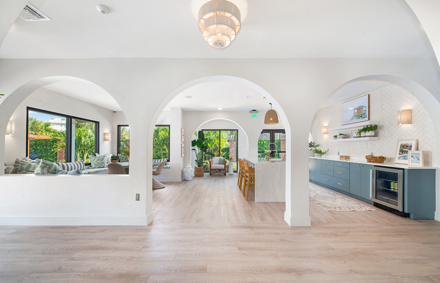 a living room and kitchen with white walls and wood floors