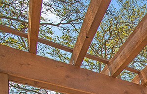 a patio with a table and chairs under a wooden roof