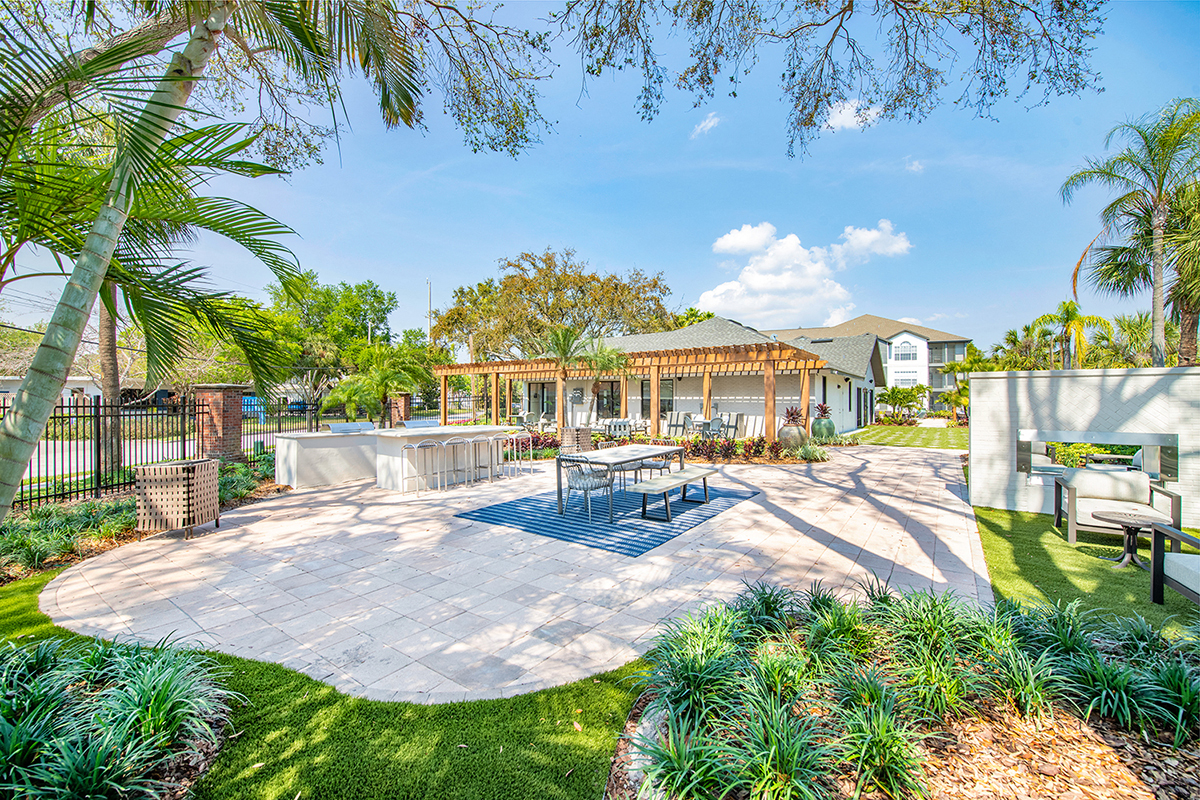a patio with a table and chairs and a house in the background