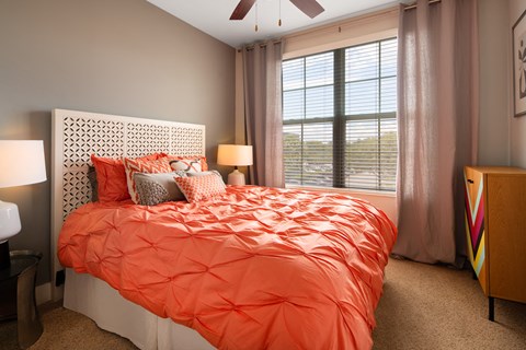 a bedroom with an orange bed and a large window
