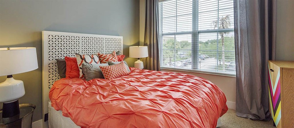 a bedroom with an orange bed and a window