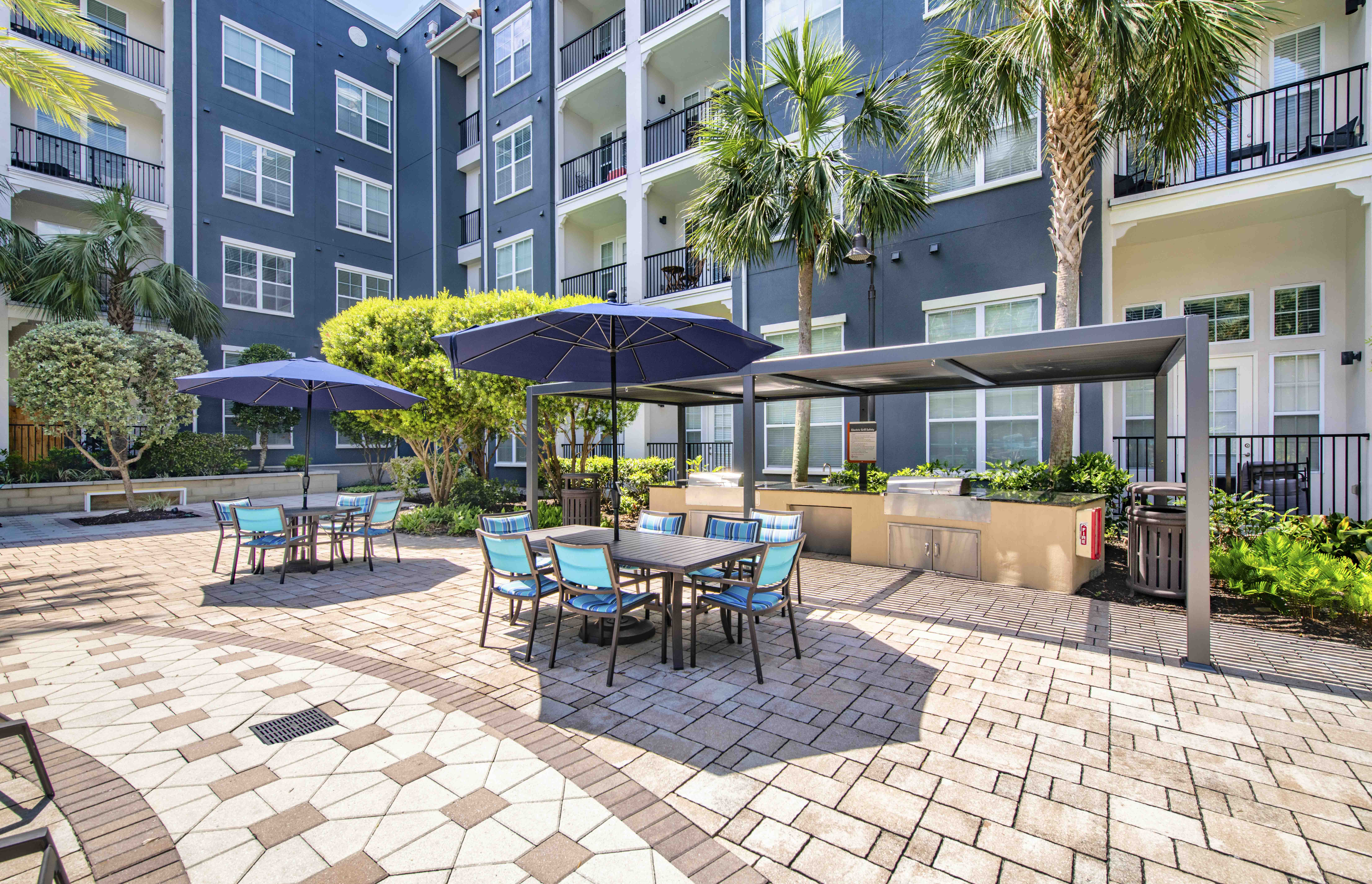 a patio with tables and umbrellas at an apartment building