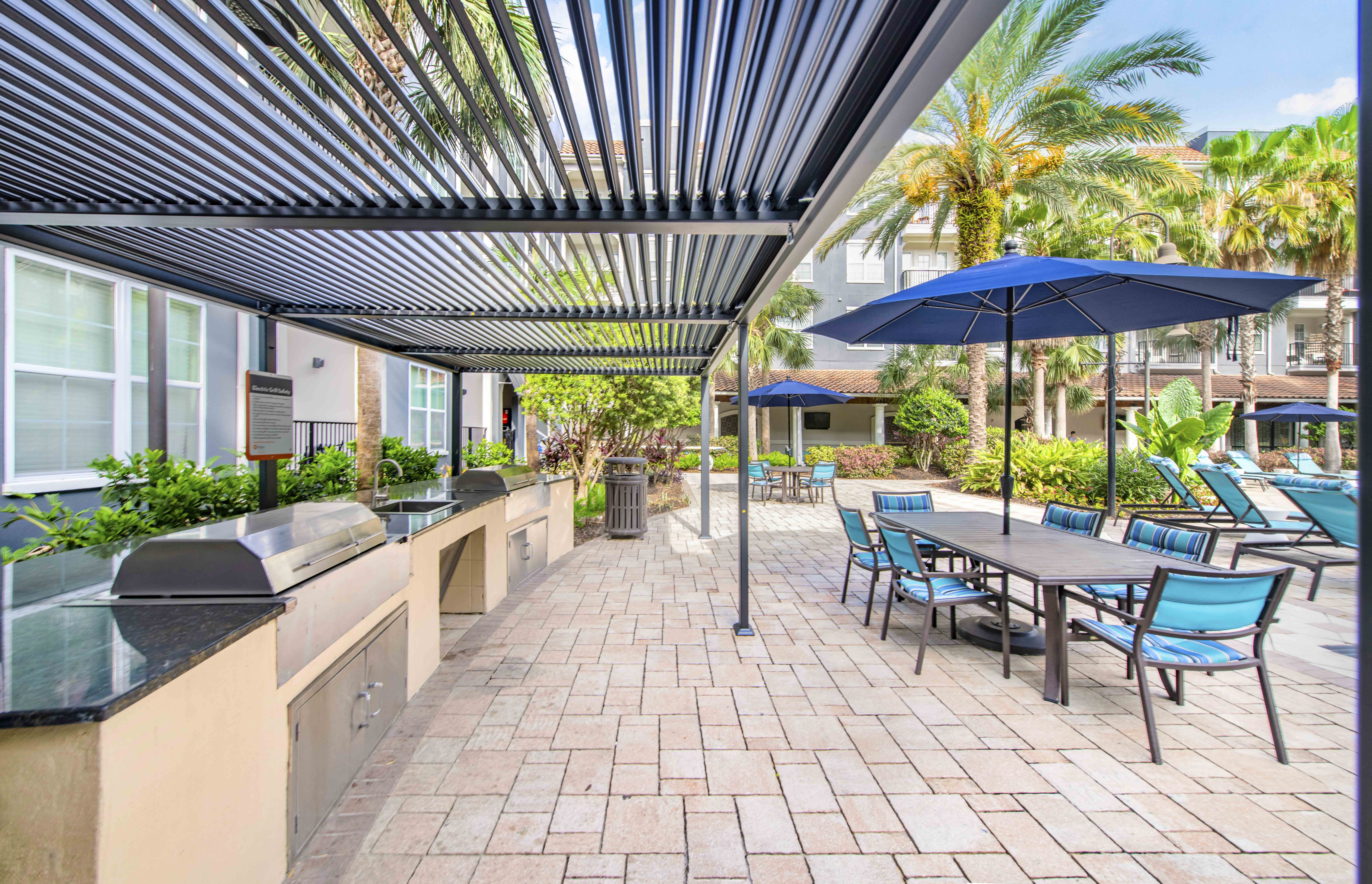 a patio with tables chairs and umbrellas and a grill