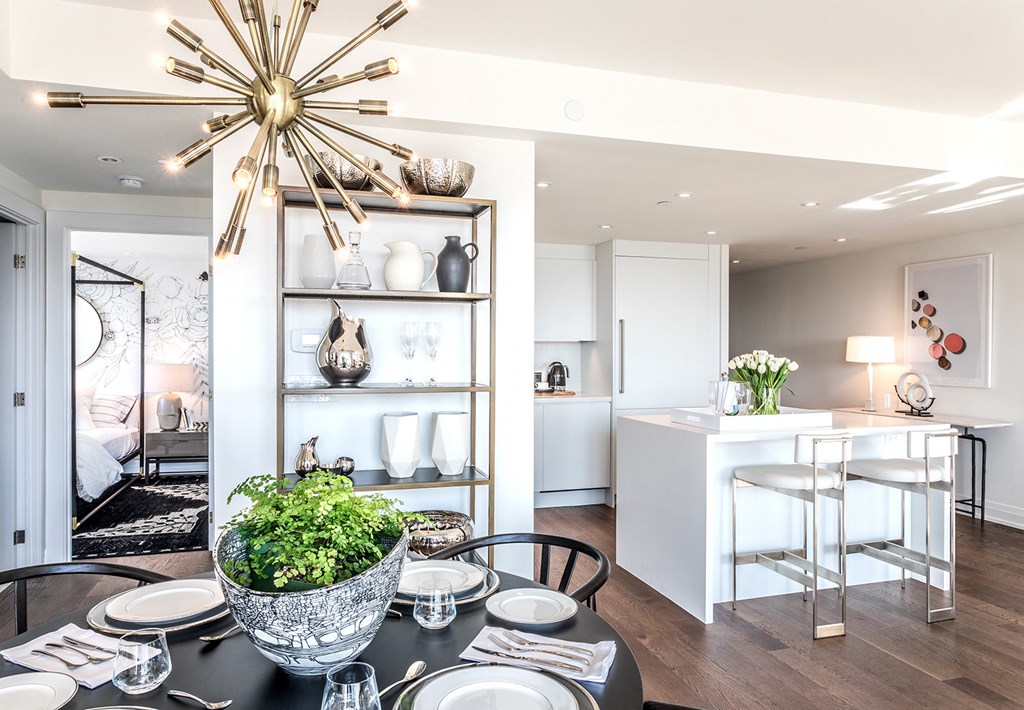 a dining room with a black table and chairs and a kitchen with a white counter