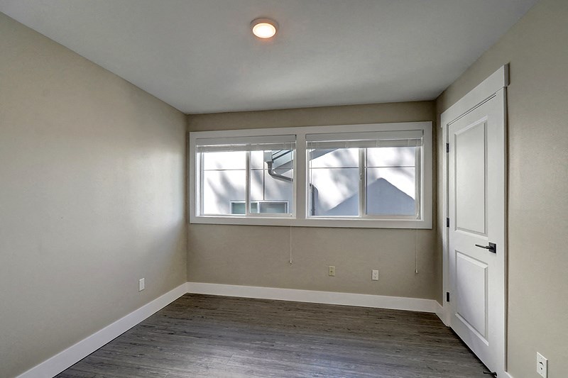 an empty bedroom with a window and a door