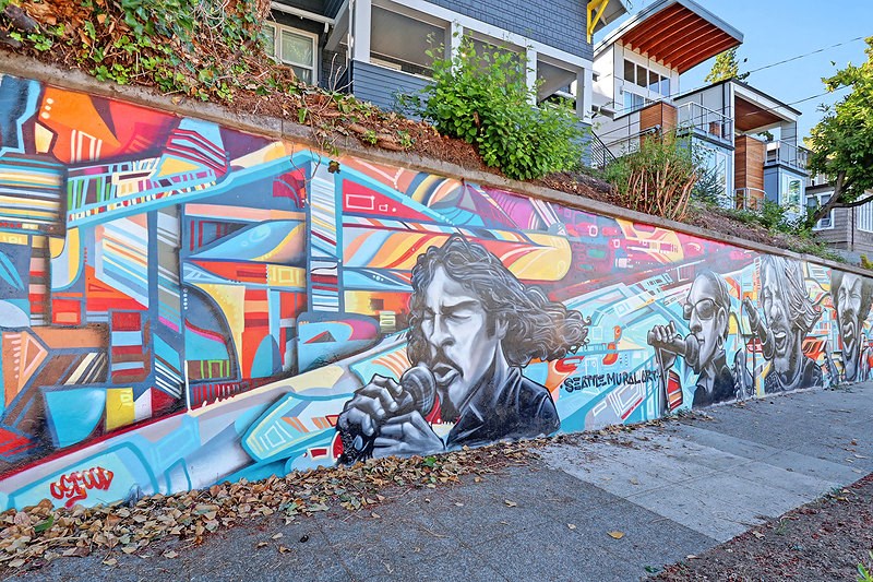 a mural on the side of a wall on a sidewalk