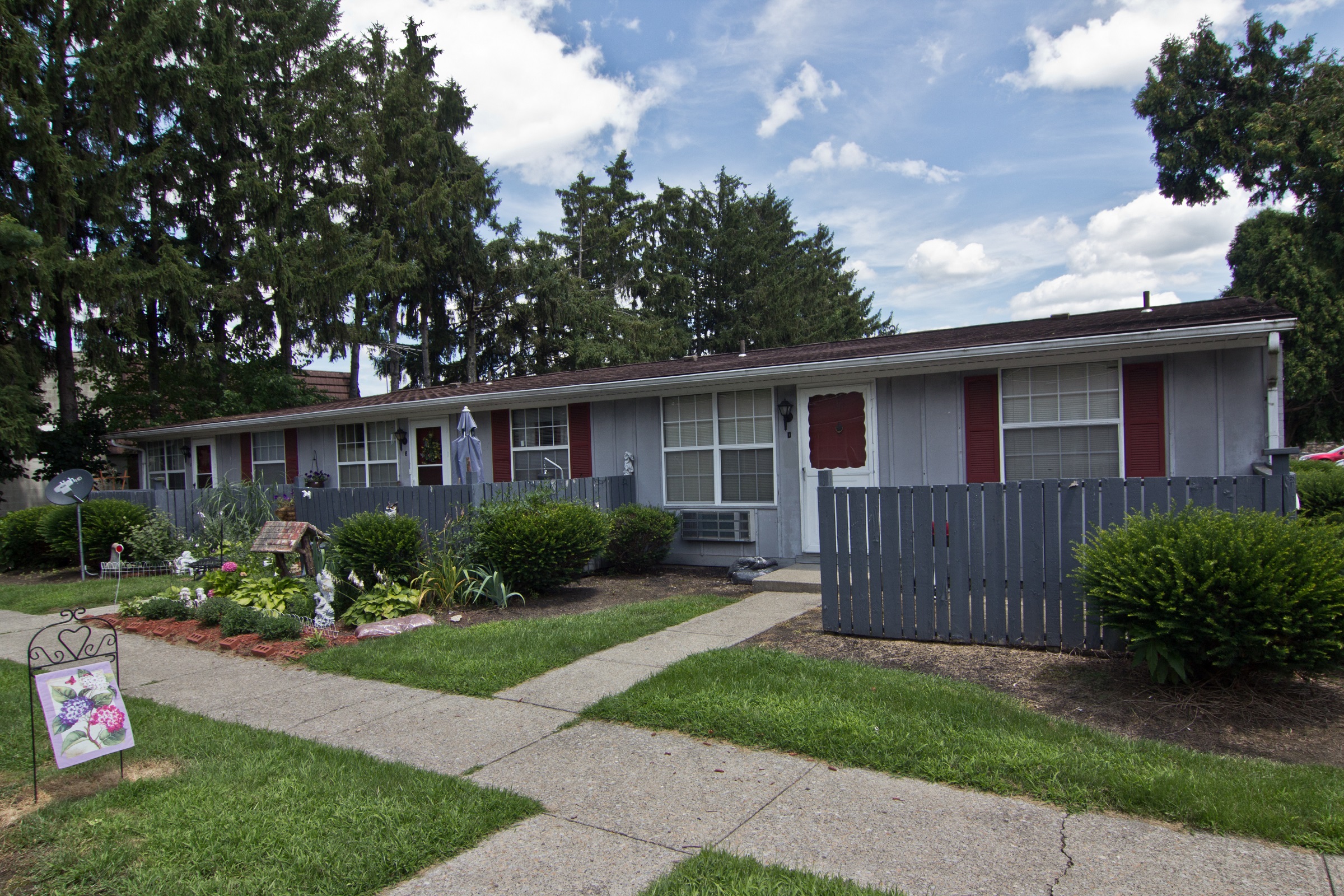 a house with a blue fence and a sidewalk in front of it
