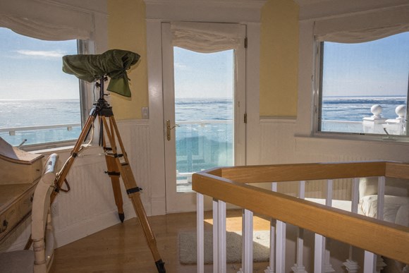 a camera tripod in a room with a view of the ocean