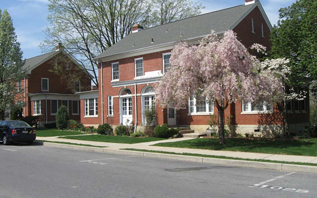 a red brick house with a pink flowering tree in front