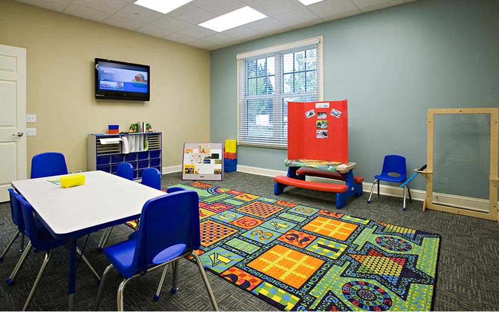 a classroom with a table and chairs and a tv